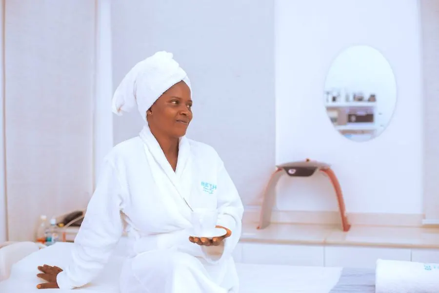 Client relaxing in a white robe holding tea after a facial treatment at Beth Beauty Aesthetic Institute