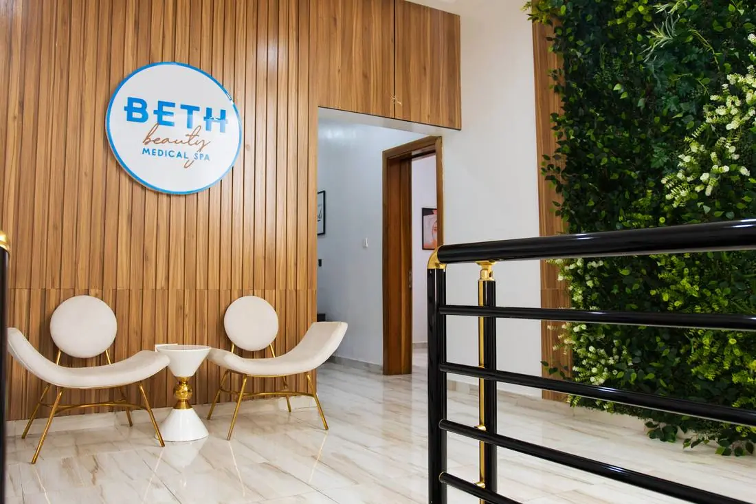 Reception lobby at Beth Beauty Aesthetic Institute with cream lounge chairs, marble floor, and a living plant wall